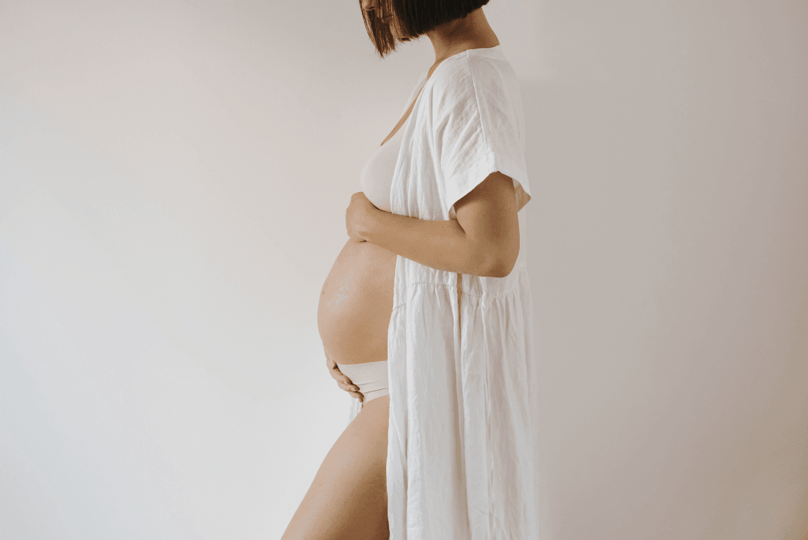 Schwangere Frau hält ihren Bauch liebevoll, Doula Begleitung